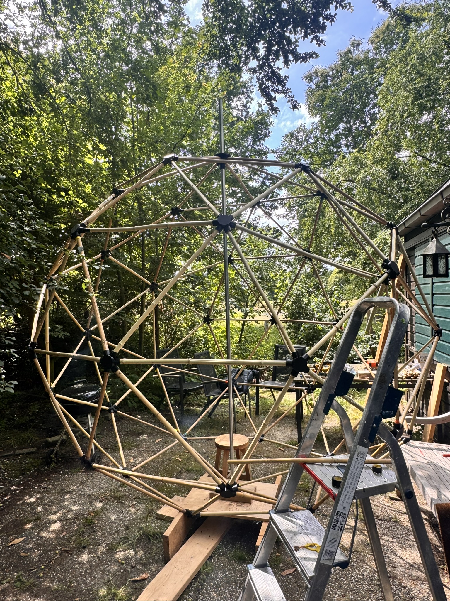The same geodesic frame at night with the addressable LED core spine glowing green through the structure.