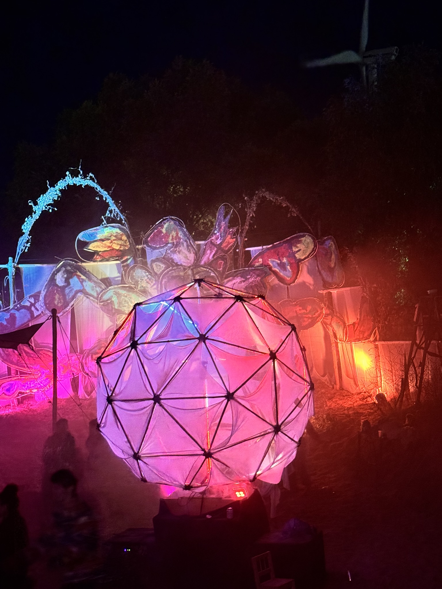 Sól at Het Landjuweel — the bamboo geodesic orb pulsing deep red through haze at night.