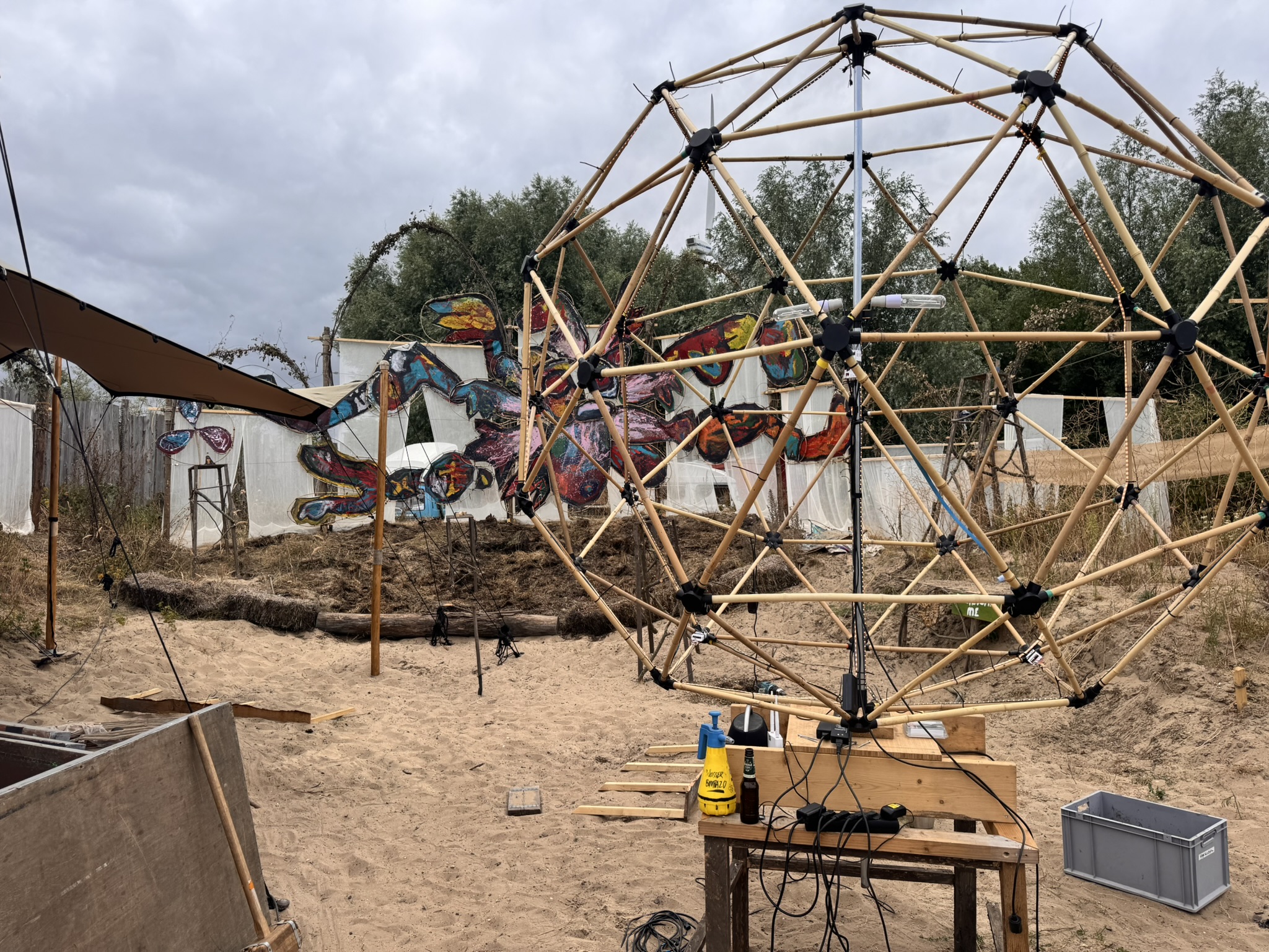 Sól's bare bamboo geodesic frame standing on the sand on site before skinning.